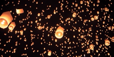 Hundreds of sky lanterns glowing orange across the night sky at Yi Peng in Chiang Mai