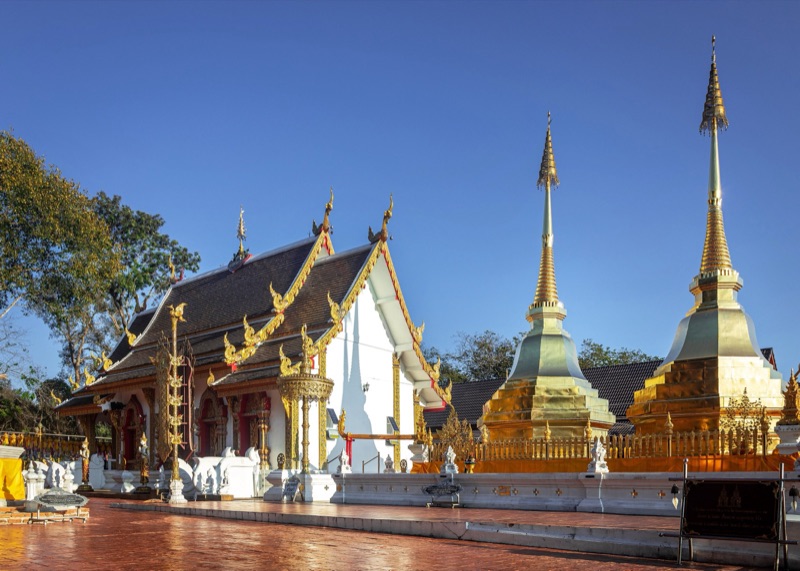 The twin golden chedis of Wat Phra That Doi Tung beside a Lanna vihara, Chiang Rai: the birth-year relic for people born in the kai (pig) year