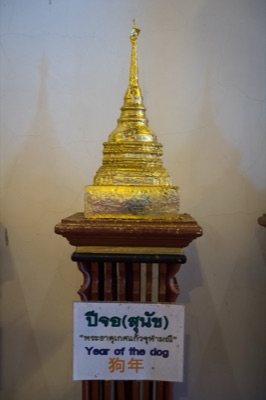 Gilded model chedi on a wooden stand, its sign naming the dog year relic, at Wat Phra Singh, Chiang Mai