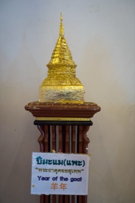 Gilded model chedi on a wooden stand, its sign naming the goat year relic, at Wat Phra Singh, Chiang Mai