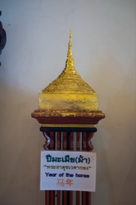 Gilded model chedi on a wooden stand, its sign naming the horse year relic, at Wat Phra Singh, Chiang Mai