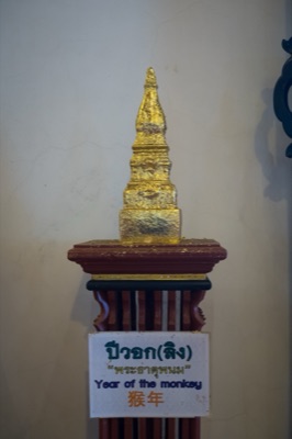 Gilded model chedi on a wooden stand, its sign naming the monkey year relic, at Wat Phra Singh, Chiang Mai