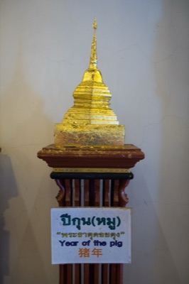 Gilded model chedi on a wooden stand, its sign naming the pig/elephant year relic, at Wat Phra Singh, Chiang Mai