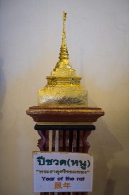 Gilded model chedi on a wooden stand, its sign naming the rat year relic, at Wat Phra Singh, Chiang Mai