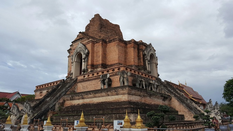 Wat Chedi Luang in the heart of Chiang Mai, a huge brick stupa with a broken top, elephant sculptures around the base and naga stairs, under a cloudy sky