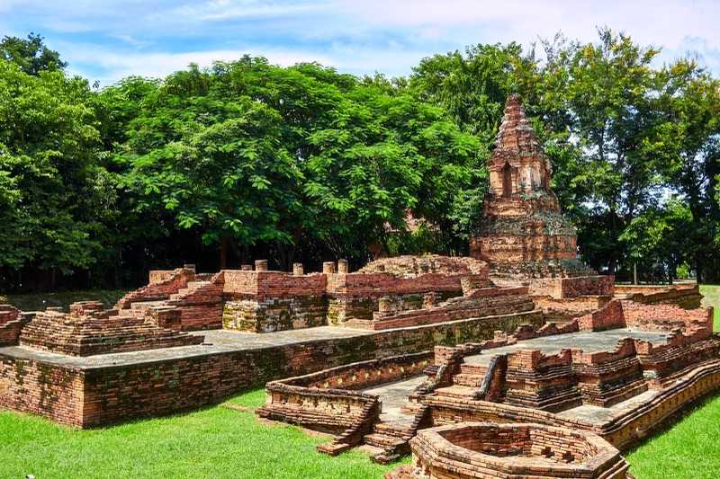 Brick temple foundations and an old stupa at Wiang Kum Kam, surrounded by lawn and big trees