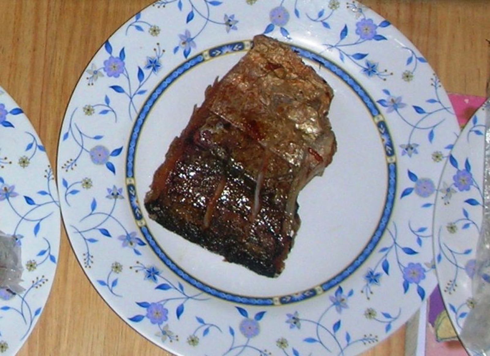 A piece of fried fermented silver barb with dark brown crisp skin on a white china plate with a blue flower pattern