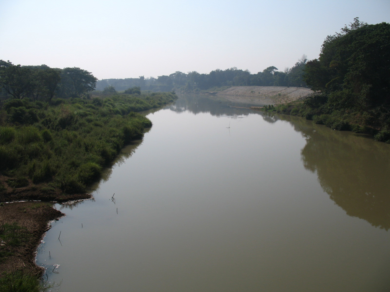 The brown Yom River flowing wide across the plain in Phrae Province, scrub and green bushes on both banks, under a hazy sky