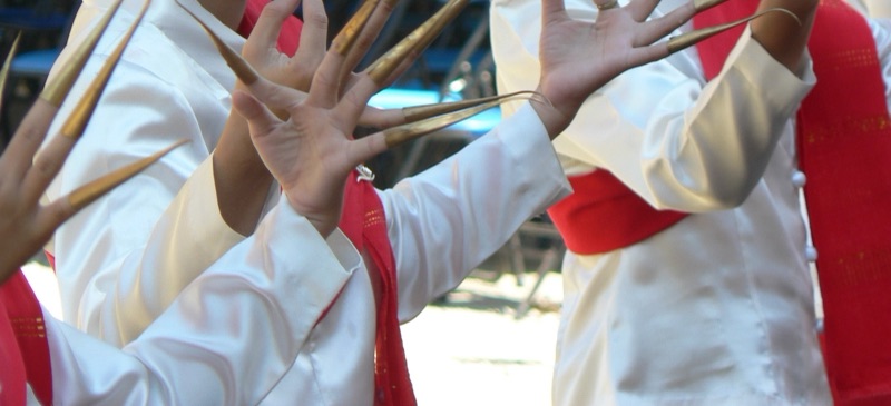 มือของช่างฟ้อนหลายคนสวมเล็บยาวสีทองทุกนิ้ว เสื้อขาว ผ้าคาดแดง ขณะฟ้อนเล็บที่เชียงใหม่