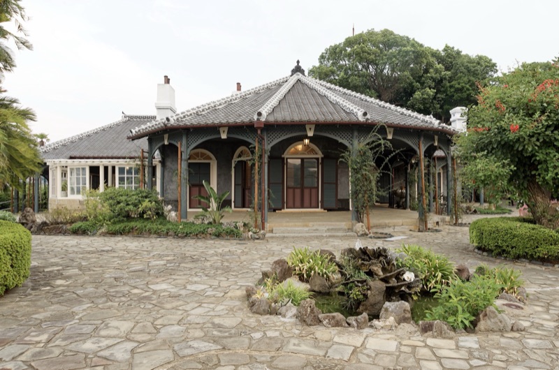 บ้านไม้ชั้นเดียวแบบตะวันตกหลังคากระเบื้อง มีระเบียงโค้ง ลานหินและสวนหย่อมอยู่ด้านหน้า
