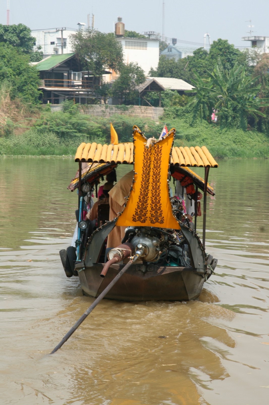 A replica scorpion-tail boat with a decorated curved stern, sailing on the Ping River in Chiang Mai