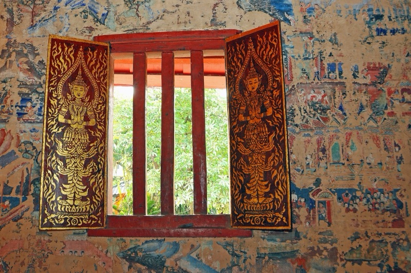 หน้าต่างลายคำในวิหารลายคำ วัดพระสิงห์ เชียงใหม่ ล้อมด้วยจิตรกรรมฝาผนังแบบล้านนาที่เล่าเรื่องวรรณกรรม