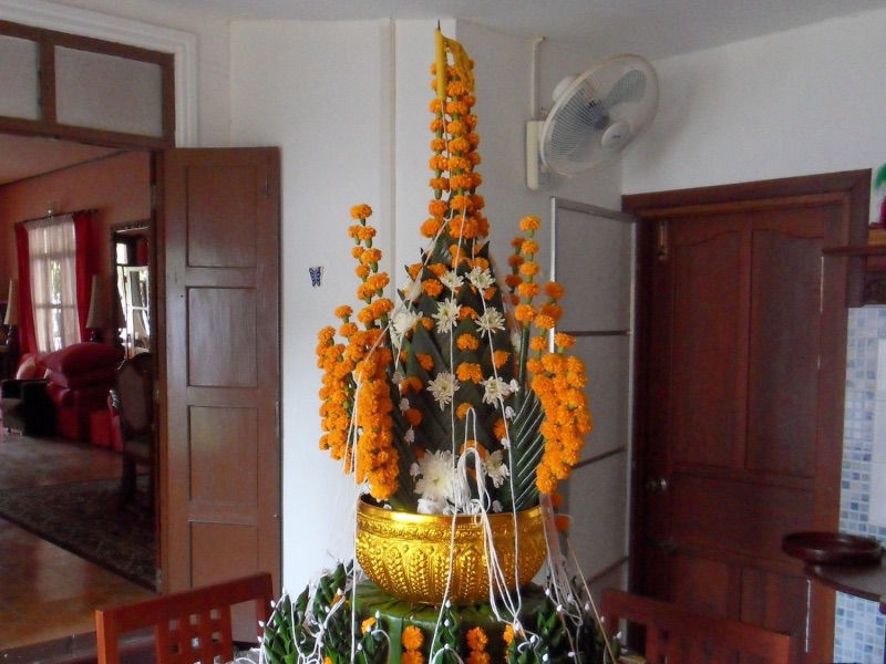A tall khwan tray decorated with marigolds, white flowers and wrist-tying threads, after a soul-calling ceremony