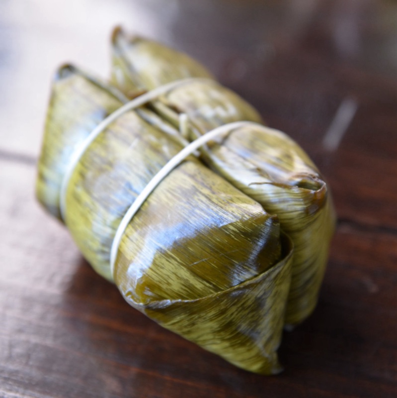 Two khao tom mat with banana filling, wrapped in banana leaf and tied as a pair with string