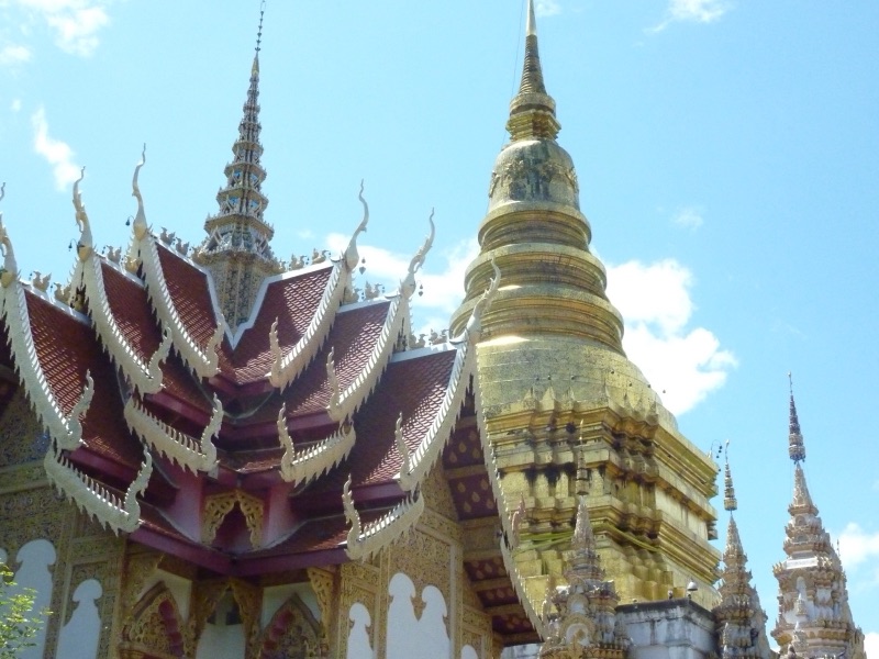 พระเจดีย์สีทองและหลังคาวิหารซ้อนชั้นสีแดงประดับช่อฟ้า ที่วัดพระพุทธบาทตากผ้า อำเภอป่าซาง จังหวัดลำพูน