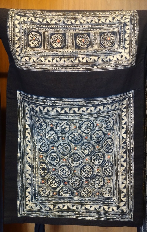 A baby carrier with white geometric embroidery on dark indigo cloth