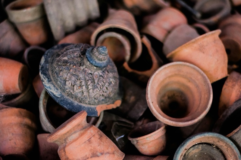 A pile of small earthenware pots of several shapes in orange-brown