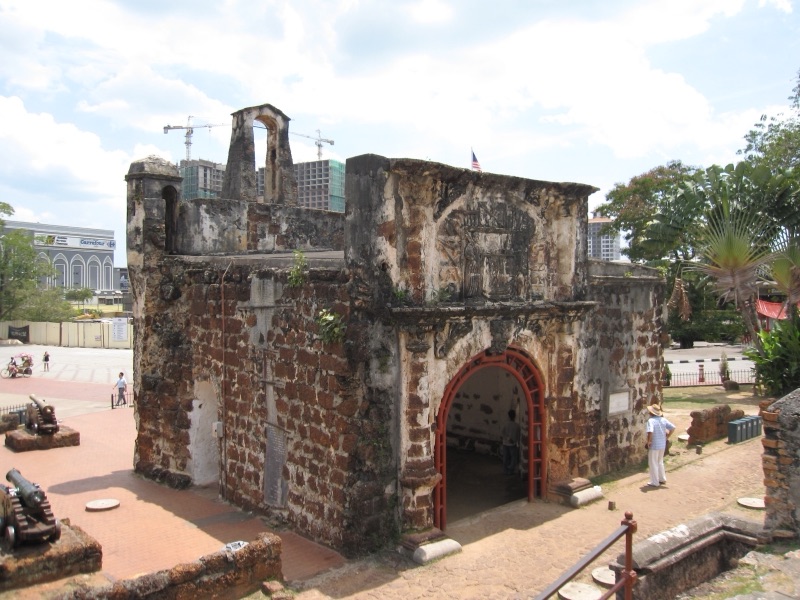 The Porta de Santiago, an old red-brown brick and stone gateway of the A Famosa fort in Melaka, with an old cannon beside it