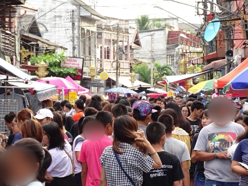 ผู้คนเดินเบียดกันในถนนคนเดินกาดกองต้า ถนนตลาดเก่า เมืองลำปาง สองข้างทางเป็นร้านค้าและตึกเก่า