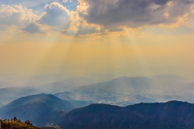 Hikers watching sunbeams break through clouds over the ridges on the Kiew Mae Pan trail, Doi Inthanon