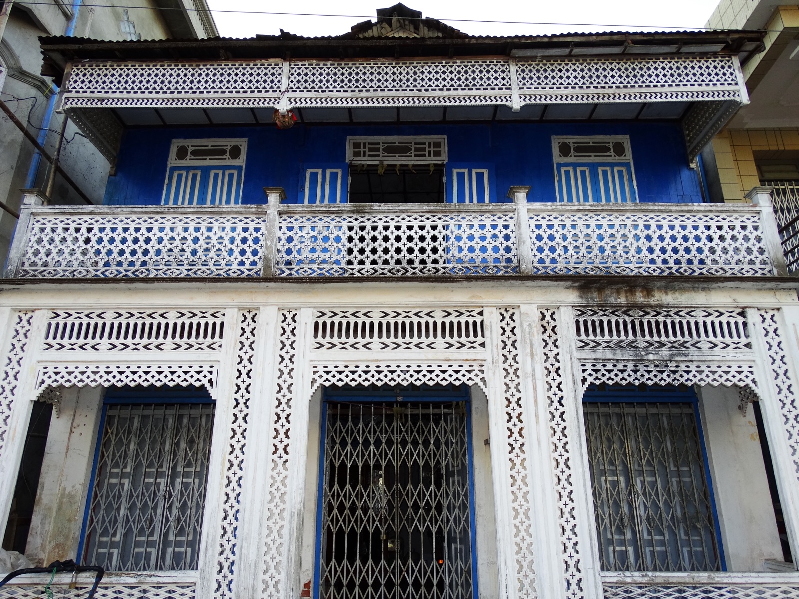 Faded colonial-era building with a veranda and wooden shutters in Mawlamyine, Myanmar