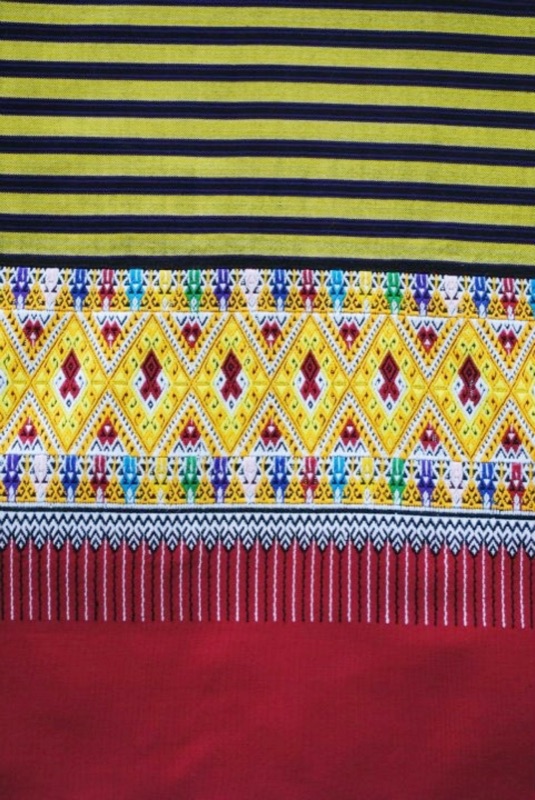 A Mae Chaem sin tin chok skirt with yellow and black horizontal stripes, a patterned hem and a red border