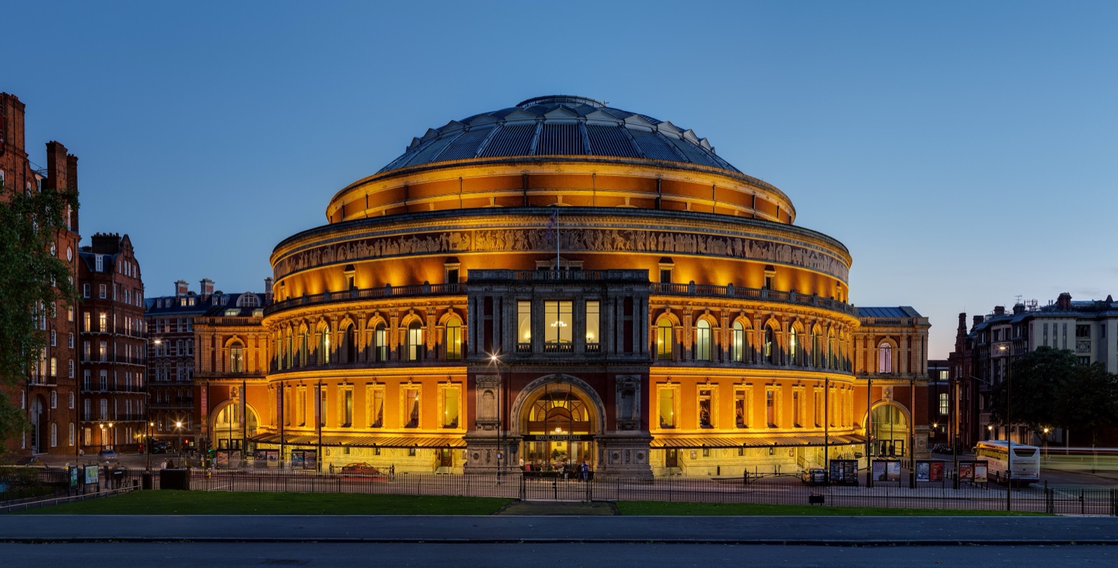 อาคารทรงกลมของ Royal Albert Hall กรุงลอนดอน ยามค่ำ มีไฟสีส้มสว่างทั่วทั้งหลัง