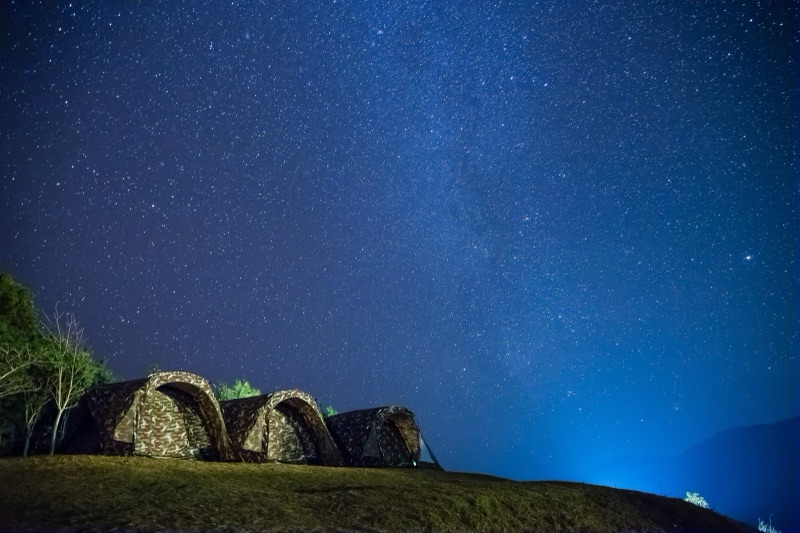 A night sky full of stars over a tent on a grassy hilltop at Doi Samur Dao, Si Nan National Park, Nan province