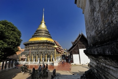 เจดีย์ทรงระฆังสีทองวัดพระธาตุลำปางหลวง กับวิหารไม้ด้านข้าง