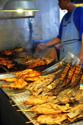 Fish and chicken grilling over charcoal at a stall in Thanin market, Chiang Mai