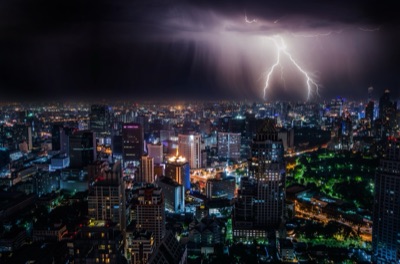 A purple bolt of lightning over tall buildings at night