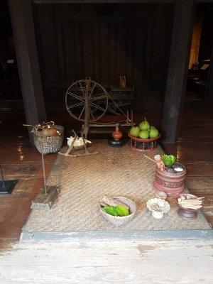 A large wooden spinning wheel on a mat in a wooden house