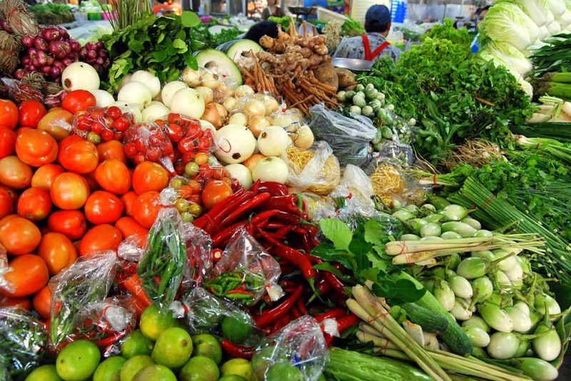 แผงผักและสมุนไพรในกาดธานินทร์ เชียงใหม่ มีมะเขือเทศ พริก ตะไคร้ มะเขือเปราะ ผักใบเขียว และผักกาดขาว